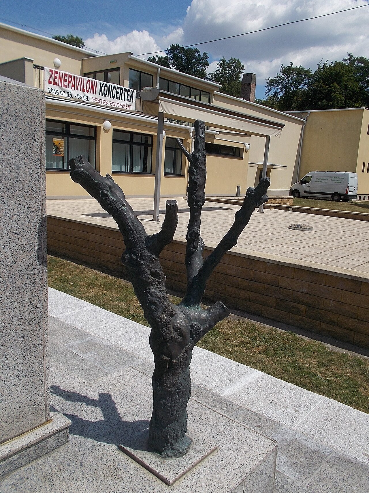 : Memorial of the victims of the 1919 red terror by Gábor Domonkos (2000 bronze relief on granite base and wall) Mother and child light a candle in memory of the martyrs. Part the monument is a dried tree (bronze tree) as a symbol of the passing of life. - 36 Szent István tér, Downtown, Csorna , Győr-Moson-Sopron County , Hungary .